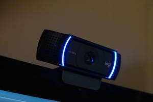 在低光環境下，顯示器上的黑色Logitech網絡攝像頭帶有藍色燈光。