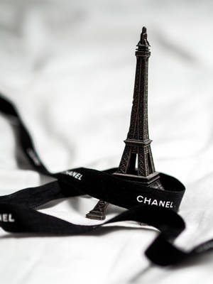 微型艾菲爾鐵塔模型在黑色 Chanel 絲帶上，襯以白色布料。