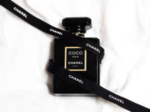 黑色 Chanel Coco Noir 香水瓶包裹黑色絲帶放在白色布料上。