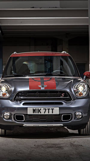 銀色Mini Countryman S，帶紅色車頂和賽車條紋，停放在車庫中。