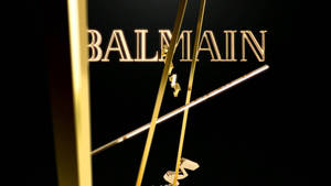 金色 Balmain 標誌與金屬棒在黑色背景上。