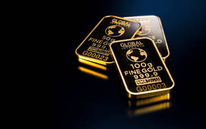 三塊金條，標有100g fine gold 999.9，放在深色反光表面上。 — 金色美學 GIF 壁紙