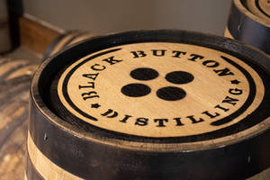 帶有 Black Button Distilling 標誌的威士忌酒桶特寫。 — 木紋 壁紙