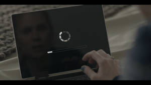 藍色指甲的手靠近筆記型電腦，顯示載入進度條和臉部反射。 — Netflix GIF 壁紙