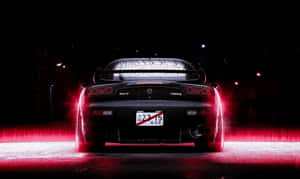 黑色Mazda RX-7跑車在潮濕夜街上發出紅色尾燈光芒。
