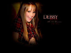 Debby Ryan 着住紅色格仔衫微笑，佢個名同標語喺深色背景上。