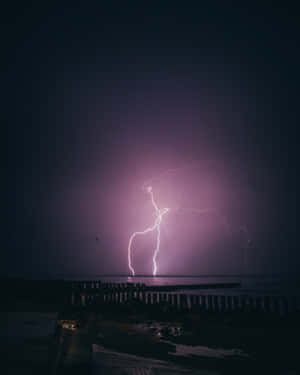 紫色閃電照亮了夜間暴風雨的海洋和木製碼頭。