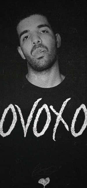Drake 身穿黑色襯衫，帶有白色 OVOXO 文字和簽名。