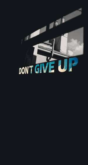 在黑暗的城市環境中透過窗戶看到的勵志文字「don't give up」。