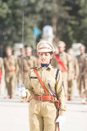 身穿卡其色制服的女兵在戶外軍事儀式中持劍。